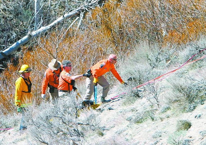 Amy Lisenbe/Nevada Appeal Carson City Search and Rescue and a Carson City firefighter work together to remove a body found near Clear Creek off Clear Creek Road Sunday morning.