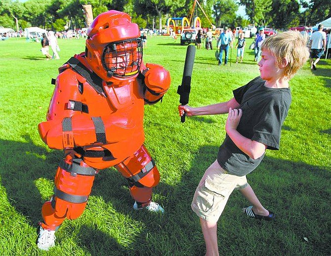 Cathleen Allison/Nevada Appeal  Kieran Henderson, 12, takes a few swings at Legislative Police Officer Nick Gillen, who wore a defensive tactics training suit during Tuesday&#039;s National Night Out event at Mills Park. For more photos visit www.nevadaappeal.com and click on photos and videos.