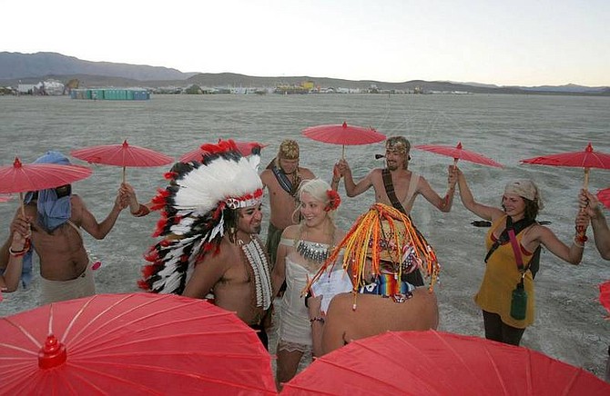Brad Horn/Nevada AppealRanger Beauty, center right, marries Alberto &quot;BBoyB&quot; Trevino, center left, and Vera Napoleon, of Chicago, on the playa at the Black Rock Desert during the Burning Man festival on Wednesday evening near Gerlach. Burning Man is an annual cultural event which starts on the Monday before, and ends on the day of, the Labor Day holiday.