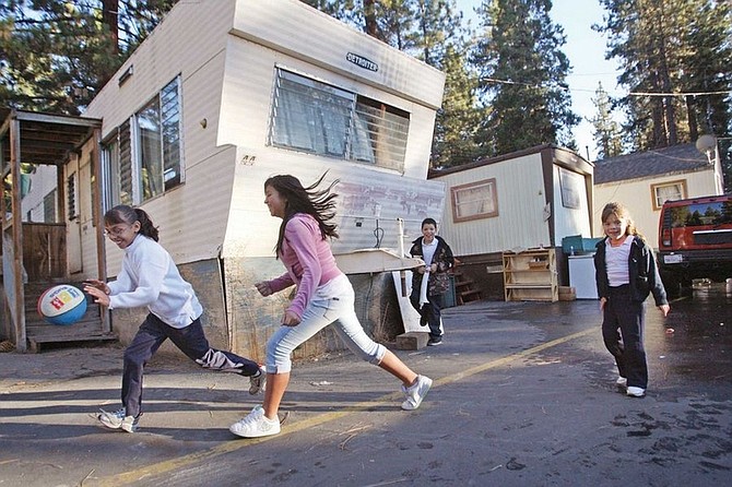 Photo - Jen Schmidt Nine-year-old Lisbeth Flores plays keep-away with neighbor Rosie Ibarra, 13,  while Flores&#039; cousins Mario, 9, and Claudia Plascencia, 6, look on Thursday afternoon in a mobile home park near Fox St. and Salmon Ave. in Kings Beach. Many families find more affordable housing in mobile homes parks, which are governed by many state, federal and local agencies.