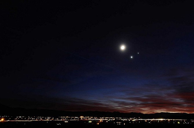 Kevin Clifford/Nevada AppealThe Moon, Venus and Jupiter light up the night sky as lights are turned on in Dayton on Monday.  The celestial objects appear bigger in the photo due to the long exposure used to capture the image.