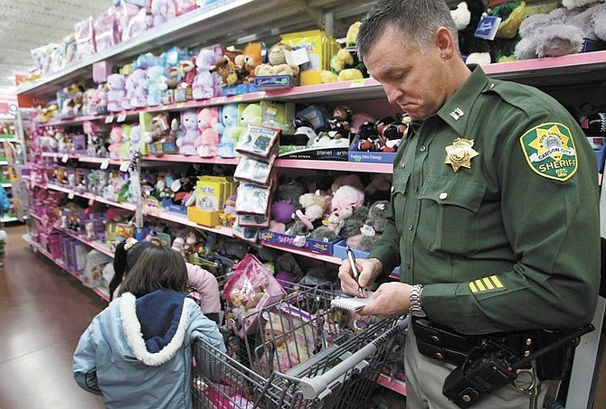 Cathleen Allison/Nevada AppealCarson City Sheriff&#039;s Capt. Ken Sandage strikes a familiar pose, but with an unfamiliar purpose, as he keeps track of items purchased by the two girls he is in charge of during the Christmas With a Cop shopping spree at Wal-Mart on Thursday.