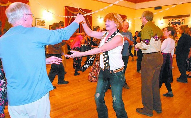 Amy Lisenbe/Nevada Appeal Teressa Tucker, center, follows Eddie Mayo&#039;s lead, left, during a Contra Dance at the Pioneer Family Dance at the Brewery Arts Center Monday evening. Attendees celebrated the new year with a variety of called dances to live music by Wild Sage, potluck snacks and desserts and a champagne and cider toast.