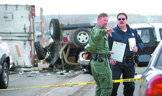Amy Lisenbe/Nevada Appeal Corrections Officer John Coleman, left, driver of the overturned Jeep, explains what he witnessed at the scene of a multiple-car accident to a Nevada Highway Patrol officer Monday afternoon on Highway 395 at the base of Spooner Summit. A semi-truck lost its brakes coming down from the summit and traveled through the intersection at Highway 395, striking a vehicle and sliding into the path of three others.