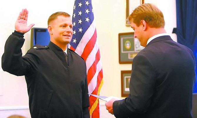 Amy Lisenbe/Nevada Appeal Lt. Cmdr. Bryan Heller, left, raises his right hand and takes an oath to become a commander as his older brother, U.S. Rep. Dean Heller, swears him in at the Governor&#039;s office Tuesday afternoon.