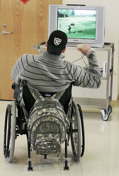 Pfc. Matthew Turpen, 22, of Des Moines, Iowa, who was paralyzed from the chest down in a car accident last year while stationed in Germany, plays golf on a Nintendo Wii video game system as part of his therapy at the Hines Veterans Affairs Hospital in Hines, Ill. The Wii system is fast becoming a craze in rehabilitation therapy for young and old patients recovering from strokes, broken bones, surgery and even combat injuries.   Photos by M. Spencer Green/ Associated Press