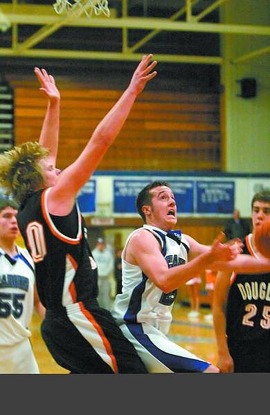 Amy Lisenbe/Nevada Appeal Carson&#039;s Rob Valerius attempts to shoot a basket as a Douglas defender reaches to block the shot Monday night at Carson High School during the boys varsity basketball game.