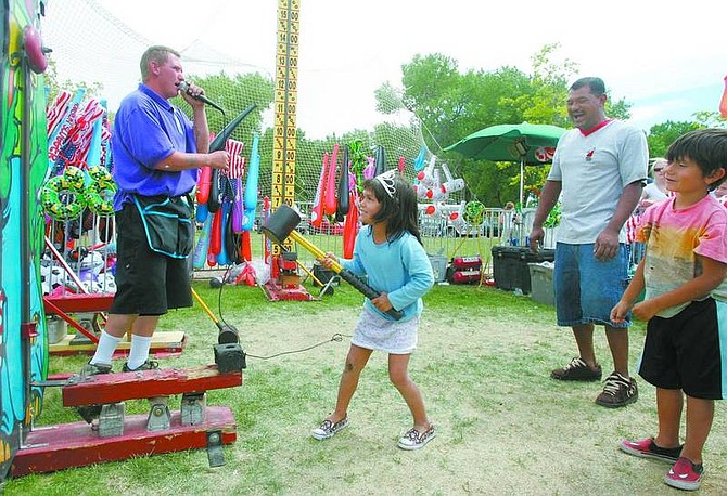 BRAD HORN/Nevada Appeal Veronica Villeda, 5, of Carson City, plays a game at the carnival while her father Nestor and brother Nestor Jr. watch on Friday.