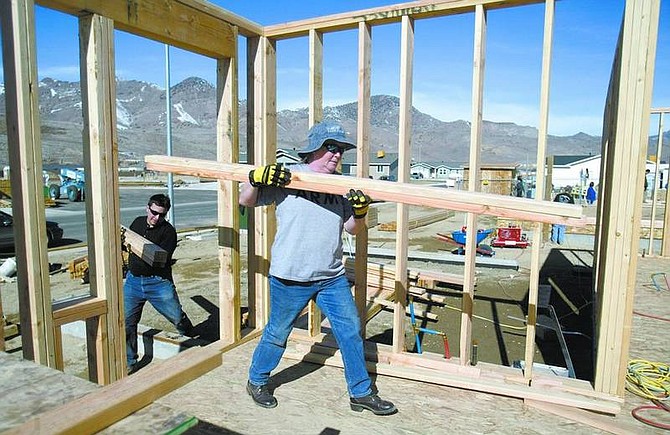 Amy Lisenbe/Nevada Appeal Friend and volunteer Linda Burkett, front, helps Marc Ramirez, left, carry lumber into the build site of his soon-to-be home Sunday morning in Dayton. Ramirez is one of nine future homeowners in the Gold Country Estates subdivision, with the assistance of the former Citizens for Affordable Homes Inc., now operated by Nevada Rural Housing Authority.