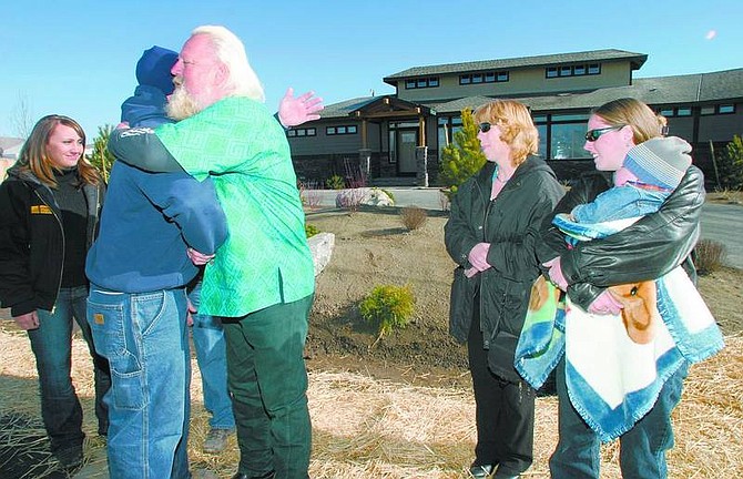 Amy Lisenbe/Nevada Appeal Steve Boettcher, center, receives a hug Saturday morning from Brian Barker of Sierra Earthworks, a Reno business. Cynthia Osborn, sales and marketing manager and community relations for West Haven Development Group, also based in Reno, is watching from the left. Mary Boettcher, her daughter Stephanie and 18-month-old grandson Joshua are standing on the right. All are in front of the new 2,700-square-foot Boettcher home in Stagecoach.