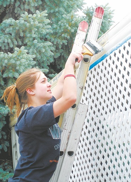 Courtesy of Chloe DeBacco Vicki Theriault paints trim at a Carson City home as part of service provided by the YES Camp. About 60 youth participated in the Catholic youth camp this week.