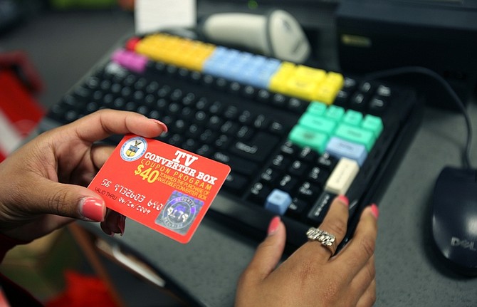 RadioShack sales representative Evelyn Rosario holds a $40 converter box coupon card as a customer purchases a conversion box to switch from analog to digital television in the Bronx borough of New York, Friday June 12, 2009. (AP Photo/David Goldman)