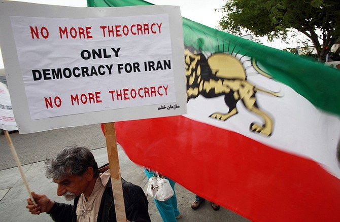 Cyrus Parsy holds a sign and a pre-revolution Iranian flag, part of a protest outside a location where Iranians can vote in the presidential election, at a hotel in Los Angeles Friday, June 12, 2009.  (AP Photo/Reed Saxon)