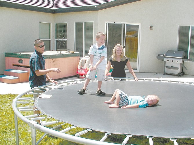 Kirk Caraway/Nevada Appeal Anthony and Michelle Charles watch sons Jacob, center, and Eli play in the backyard of their new Dayton home.