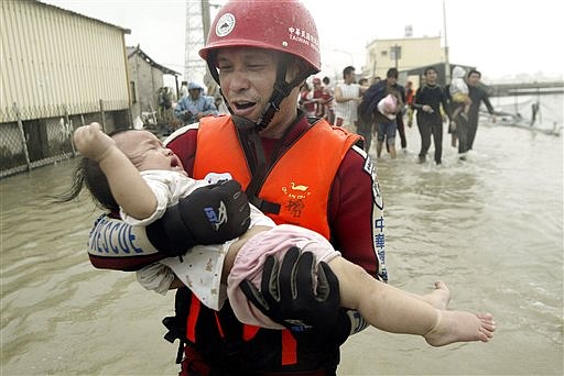 A rescuer helps a crying baby out of floodwater area after Typhoon Morakot hit Pintung county, southern Taiwan, Sunday, Aug.  9, 2009. The storm dumped more than 200 centimeters (80 inches) of rain on some southern counties on Friday and Saturday, the worst flooding to hit the area in half a century, the Central Weather Bureau reported. (AP Photo) ** TAIWAN OUT **