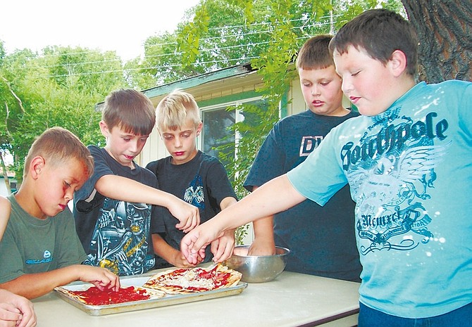 Photos by Sally J. Taylor/Nevada AppealKyle Rudy, 10, left, Bryce Newhall, 10, Justin Jackson, 10, Jayce Sulprizio, 10, and Zachary Mills, 11, all get into the act of spreading cheese on the pizza they learned to make July 30 during a cooking class at the Boys &amp; Girls Club.