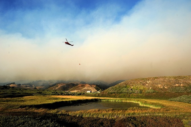 A helicopter draws water to drop on the Lockheed Fire in unincorporated Santa Cruz County, Calif., on Thursday, Aug. 13, 2009. As of Thursday evening, the fire had burned about 2,800 acres. (AP Photo/Noah Berger)
