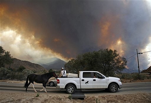 Residents help Roberto Bombalier evacuate a 2-year-old horse on foot as the Station fire burning in the Angeles National Forest above Acton, Calif. on Sunday Aug. 30, 2009. The horse had not been trained for trailer travel yet.  (AP Photo/Jason Redmond)