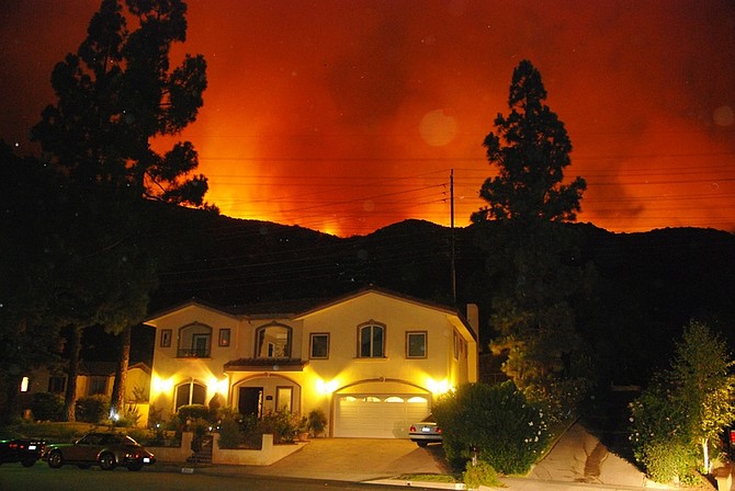 Flames from a brush fire glow from a distance behind a home on Baytree Drive in La Canada Flintridge, Calif., Friday, Aug. 28, 2009. About 500 homes in La Canada Flintridge, a suburb just 12 miles north of downtown Los Angeles, also were ordered evacuated late Thursday as flames made their way slowly down from the San Gabriel Mountains, said Forest Service fire spokeswoman Diane Cahir. (AP Photo/Mike Meadows)
