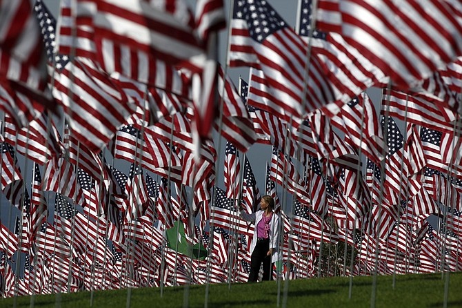 Marnie Mitze, from Pepperdine University, walks among thousands of American flags at a memorial honoring the victims of the Sept. 11, 2001 terrorist attacks, set by volunteers at the campus lawn in Malibu, Calif. on Friday, Sept. 11, 2009. One flag for each of the nearly 3,000 lives lost on that tragic day. The installation of the flags be on display Sept. 11 to 18. (AP Photo/Damian Dovarganes)