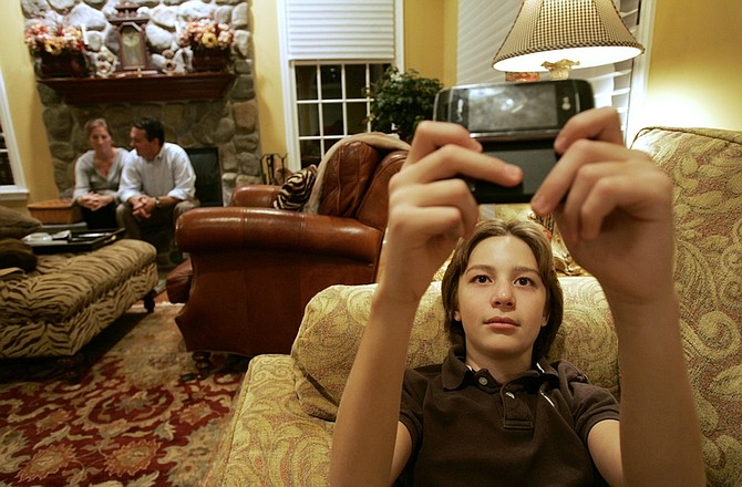 Dylan Herina 13, uses his cell phone to text as his mother and father, Beth and Peter sit in another part of their family room in their home in Ringwood N.J., Wednesday, Sept. 30, 2009. Dylan has strict rules as to when and where he can text. (AP Photo/Rich Schultz)