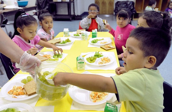 In this photograph taken Friday, Oct. 2, 2009, Jean Carlos Rubell, 3, helps himself to grapes during preschool lunch at the Latin American Community Center in Wilmington, Del. (AP Photo/ Steve Ruark)