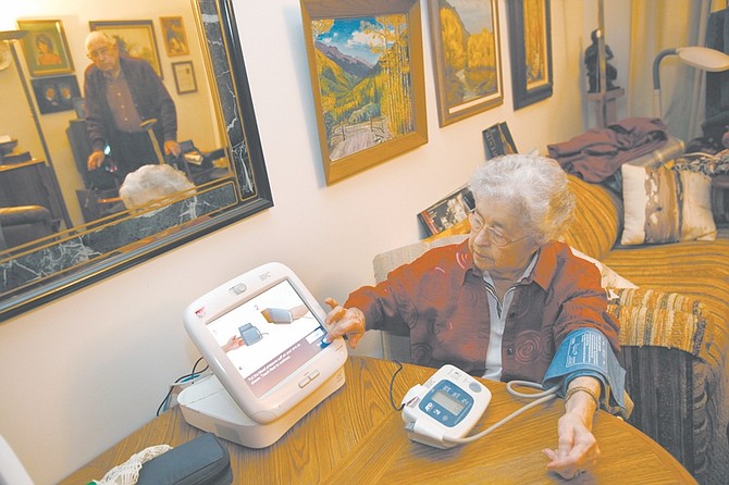 Juanita Wood transmits her blood pressure readings to a clinic; her husband, Arthur, seen in the mirror, uses a similar device. The Woods live in Maryland. Illustrates HEALTH-TECH (category l), by Elizabeth G. Olson, special to The Washington Post. Moved Wednesday, Nov. 18, 2009. (MUST CREDIT: Photo for The Washington Post by Susan Biddle.)