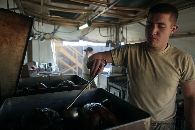 Spc. Seth Breesawitz of Springfield, Mo. head cook for the Able Troop 3-71 Cavalry Squadron, uses a ladle to baste his turkeys as he prepares Thanksgiving dinner for the troops at the Joint Combat Operations Post in the town of Baraki Barak district, Logar province, Afghanistan Thursday Nov. 26, 2009. (AP Photo/Dario Lopez-Mills)