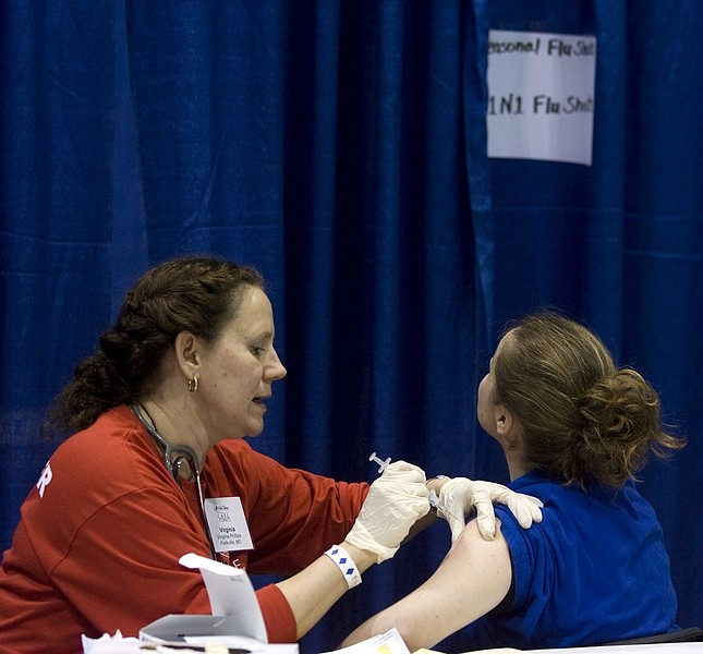 Volunteer nurse Virginia Phillips, left, administers a H1N1 flu shot to Crystal Sickles at a free clinic at Bartle Hall Wednesday, Dec. 9, 2009, in Kansas City, Mo. Sickles was one of about 1,000 people who showed up to the free clinic sponsored by the nonprofit National Association of Free Clinics.  (AP Photo/Ed Zurga)