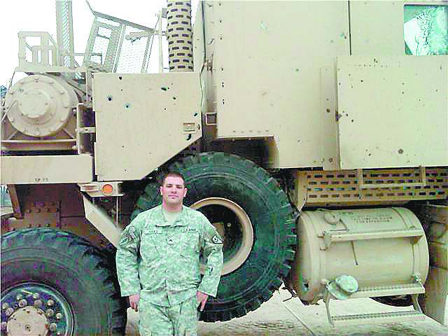 Courtesy of Justin HawsSgt. Justin Haws, and just some of the small arms and shrapnel damage to his HET. Note the baseball-size hole in the fuel tank at the lower right, and the exploded armored window in the upper right.