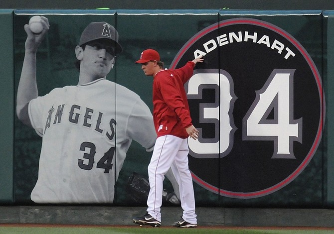 ** FOR USE AS DESIRED, YEAR END PHOTOS ** FILE - Los Angeles Angels  starting pitcher Jered Weaver pays his respect at a center field banner of Los Angeles Angels rookie pitcher Nick Adenhart who was killed early Thursday in an auto accident in Fullerton, Calif., before their baseball game with the Boston Red Sox in Anaheim, Calif., in this April 10, 2009 file photo. (AP Photo/Chris Carlson, File)
