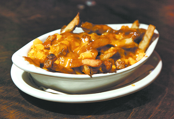 This photo taken Jan. 11, 2010 shows a serving of poutine  at New York&#039;s Dive Bar. This guilty pleasure of extra-crispy french fries, meaty gravy and cheese curds has been called the national dish of Canada. (AP Photo/Richard Drew)