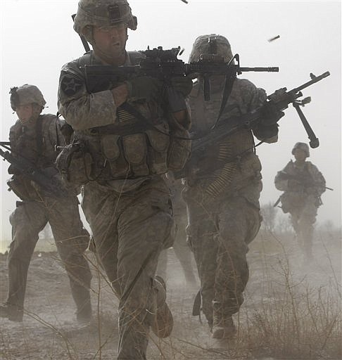 A U.S. soldier returns fire as others run for cover during a firefight with insurgents in the Badula Qulp area, West of Lashkar Gah  in Helmand province, southern Afghanistan, Sunday, Feb. 14, 2010.  The area is near Marjah, where U.S. Marines are conducting an offensive against the Taliban. (AP Photo/Pier Paolo Cito)