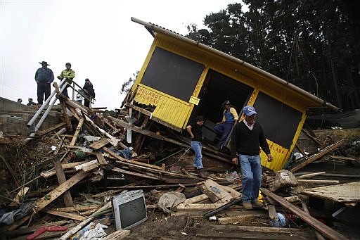 People survey a destroyed house after an earthquake in Curanipe, some 389 km., about 241 miles, southwest Santiago, Sunday, Feb. 28, 2010. A 8.8-magnitude earthquake struck central Chile early Saturday.  (AP Photo/Roberto Candia)