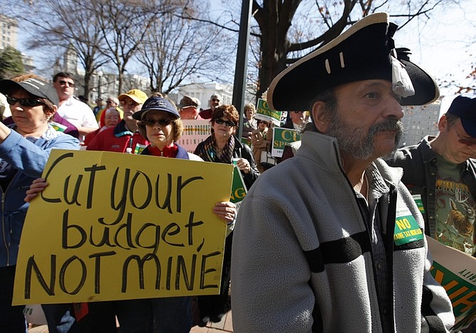FILE - In this March 8, 2010 file photo, Tea Party member Greg Hernandez, of Quicksburg, Va., wearing a tri-corner  hat and tea bag,  listens to speakers during a rally at the Capitol  in Richmond, Va.    (AP Photo/Steve Helber/file)
