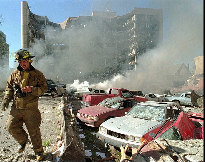 FILE - In this April 19, 1995 file photo, an Oklahoma City fireman walks near explosion-damaged cars on the north side of the Alfred Murrah Federal Building in Oklahoma City after a car bomb blast. More than 600 people were injured in the attack and 168 people were killed. Timothy McVeigh was executed in 2001 and Terry Nichols is serving multiple life sentences on federal and state convictions for their convictions in the bombing. (AP Photo/The Daily Oklahoman, Jim Argo, File) MANDATORY CREDIT