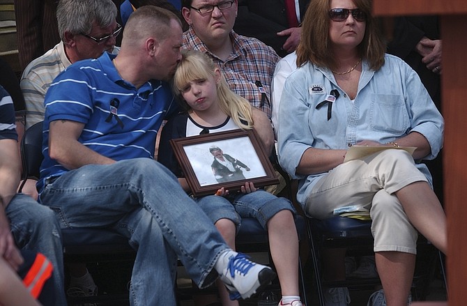 Miner Phillip Cash, left, kisses his daughter Hannah Cash, center, 7, as she holds a picture of her grandfather Michael Elswick during a ceremony at the state Capitol in Chalreston, W.V. Monday, April 12, 2010 for the miners killed in the Upper Big Branch mine explosion last week. Michael Elswick was one of the 29 miners killed in the Upper Big Branch mine explosion last week. His daughter Jamie, Hannah&#039;s mother, is at right.  (AP Photo/Charleston Daily Mail, Tim Hindman)