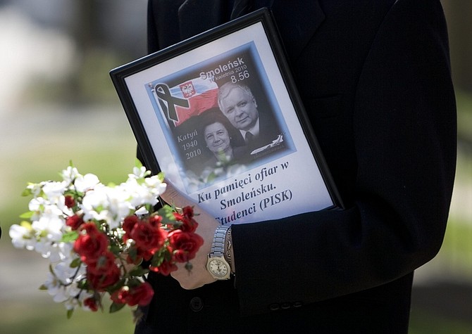 A mourner carries a tribute to the Polish President Lech Kaczynski upon arriving at a ceremony at the Katyn memorial in Toronto on Sunday, April 11, 2010. The ceremony, initially organized to mark the 70th anniversary of the Katyn massacre, was dominated by remembrance for the Polish President Lech Kaczynski  who died alongside 95 other passengers after their plane crashed in Smolensk, Russia on Saturday. (AP Photo/The Canadian Press, Chris Young)
