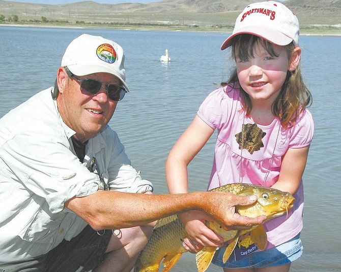 Mike Sevon/For the Nevada Appeal Larry Harris, then-volunteer with NDOW, lends a hand to Morgan Tisdale with a big fish from a recent Kids Carp Derby. Many fish this size will be caught on Saturday at Lahontan Reservoir where the 9th annual derby will take place.