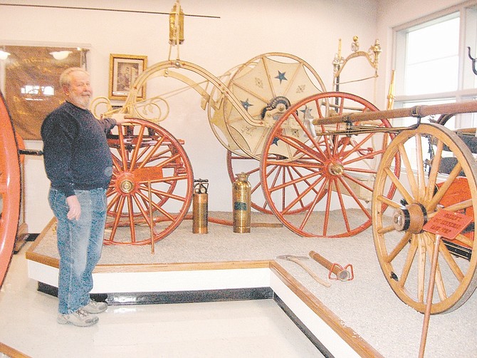 Courtesy Sue Morrow Paul Webster, Warren Engine Co. No. 1 volunteer fire department trustee and longtime member, stands beside an antique hose cart on display in the fire museum at the Les Groth Fire Station on Stewart Street.