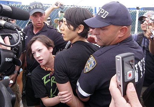 Six-time  hot dog eating contest champion Takeru Kobayashi, center, of Japan, is taken into custody by New York police officers after he jumped on stage at the end of the hot dog eating contest in New York&#039;s Coney Island on Sunday, July 4, 2010. (AP Photo/Nick Jesdanun)
