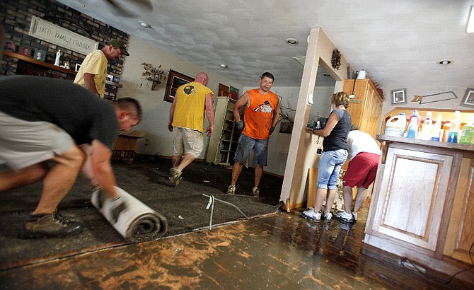 AP Photo/The Gazette, Julie KoehShane Ward, of Manchester, left, rolls up carpet in the living room of Jerry and Cheryl Gotto as other friends and family help with clean up at their home in Linden Acres on Lake Delhi on Sunday, July 25, 2010. The permanent home, which they&#039;ve lived in since 1993, retained about four and a half feet of water before the water went down.  Cheryl Gotto said her husband woke up at midnight Saturday and the two noticed the water was high in the front.  She went to the back door and found &quot;a pond&quot; in the backyard.