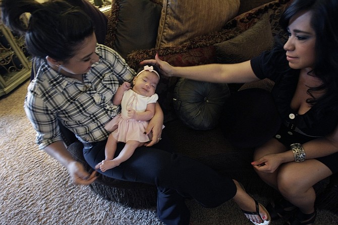 In this photo made Thursday, July 22, 2010,  Toni De La Cruz, right, touches Christina Vasquez&#039;s four month old daughter Johhnie in El Paso, Texas Thursday, July 22, 2010. Vasquez named he daughter after her father a late Border Patrol Agent. (AP Photo/LM Otero)