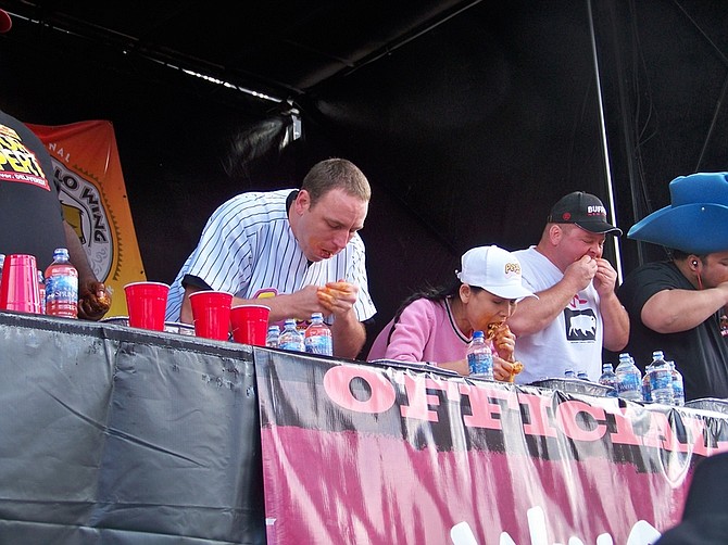 In this photo provided by National Buffalo Wing Festival, Joey Chestnut, left, competes with  Sonya Thomas, center, at 2010 Wing Fest in Buffalo, N.Y., Sunday, Sept. 5, 2010. Thomas, The Black Widow of eating contests gobbled up nearly 181 chicken wings in 12 minutes, devouring the national championship record. (AP Photo/National Buffalo Wing Festival, Brian Kahle)