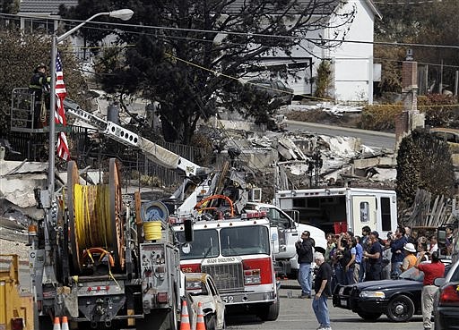 Residents, bottom right, witness the raising of a U.S. flag at the site of a gas pipeline explosion in San Bruno, Calif., Monday, Sept. 13, 2010. (AP Photo/Marcio Jose Sanchez)