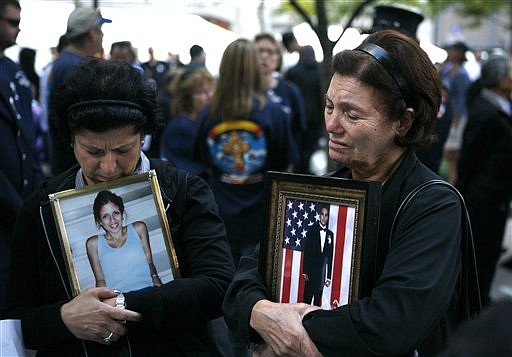 Rosa Notaro, left, and Anna Sereno, right, both of the Brooklyn borough of New York, hold photos of their children Daniella Notaro and Arturo Angelo Sereno as friends and relatives of the victims of the Sept. 11, 2001 attacks gather for a commemoration ceremony at Zuccotti Park, adjacent to ground zero, on the ninth anniversary of the terrorist attacks on the World Trade Center, Saturday, Sept. 11, 2010, in New York. (AP Photo/Jason DeCrow)
