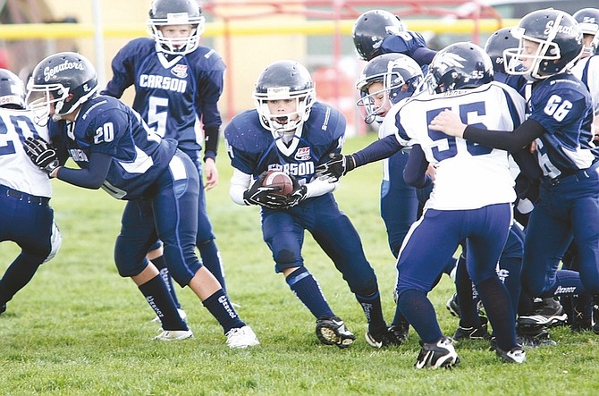 Photos by Shannon Litz/Nevada AppealDennis Krueger, center, runs as Nicholas Andreas (20) and Nicholas Tibma (66) block during the Pee Wee Senators win against Reno last weekend. For more photos go to nevadaappeal