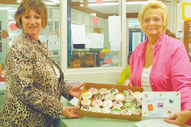 Sandi Hoover/Nevada AppealDenise DeMarzo, left, in the front office of Empire Elementary School, accepts a batch of brightly decorated birthday cupcakes from Deb Tull, organizer of the Cupcake Brigade, for a girl celebrating her birthday Tuesday.