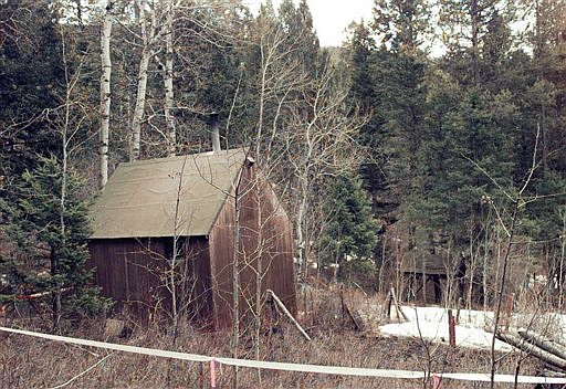 FILE - In this April 6, 1996 file photo, the cabin of Unabomber Theodore Kaczynski, partially surrounded by white, plastic tape, sits at the end of a muddy, private road, hidden in a wooded setting about 300 yards from the nearest neighbor in Lincoln, Mont. The 1.4-acre parcel of land in western Montana that was once owned by Kaczynski is on the market for $69,500. The listing offers potential buyers a chance to own a piece of &quot;infamous U.S. history&quot; and says the forested land &quot;is obviously very secluded. (AP Photo/Elaine Thompson, File)