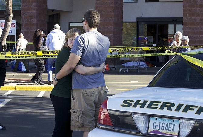 Two people embrace each other at the scene where Rep. Gabrielle Giffords, D-Ariz., and others were shot outside a Safeway grocery store in Tucson, Ariz. on Saturday, Jan. 8, 2011.(AP Photo/James Palka)